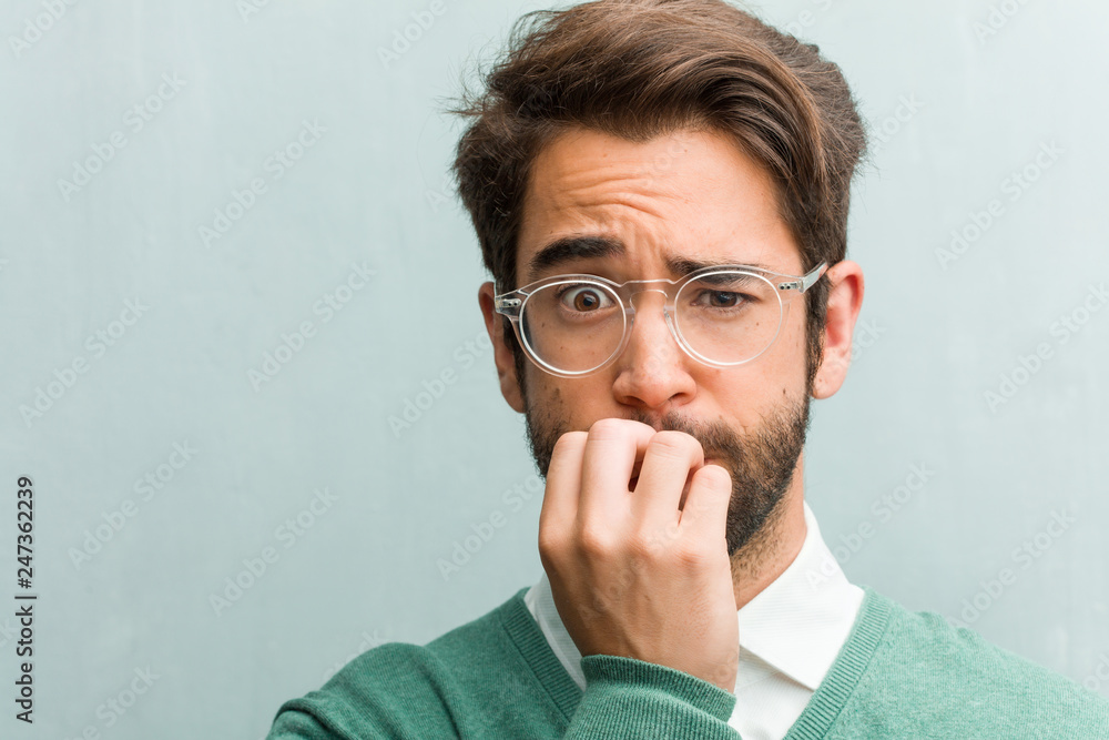 Young handsome entrepreneur man face closeup biting nails, nervous and very anxious and scared for the future, feels panic and stress Young handsome entrepreneur man face closeup biting nails, nervous and very anxious and scared for the future, feels panic and stress