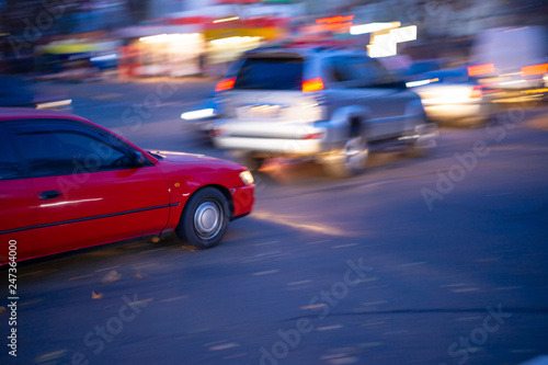 Motion blur red car photo on crossroad. Soft focus photo. Night big city life