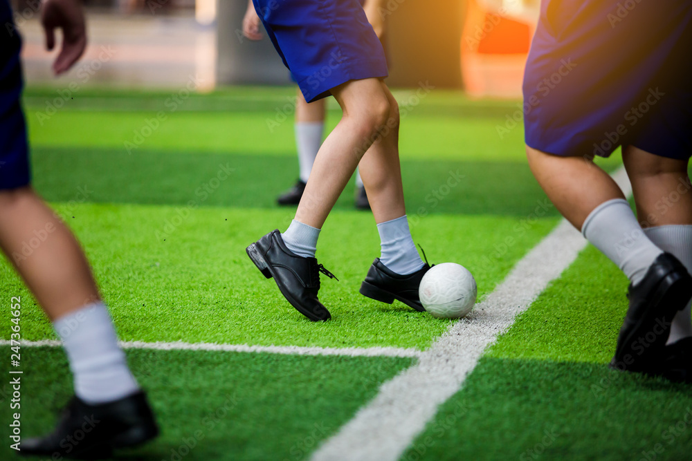 Asian student play plastic soccer ball on green artificial turf