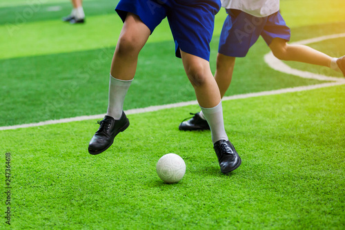 Asian student play plastic soccer ball on green artificial turf