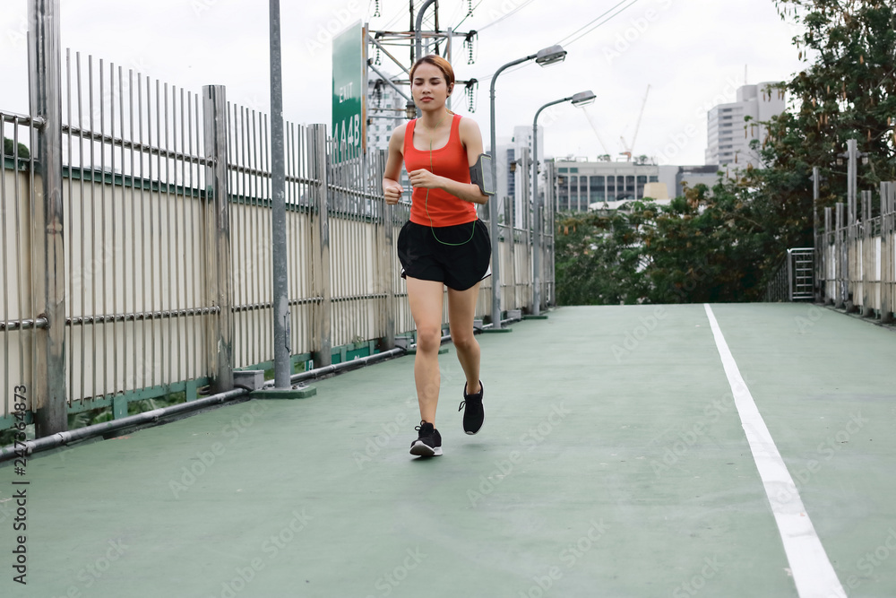 Young Asian healthy female running on street. Fitness and exercise concept.