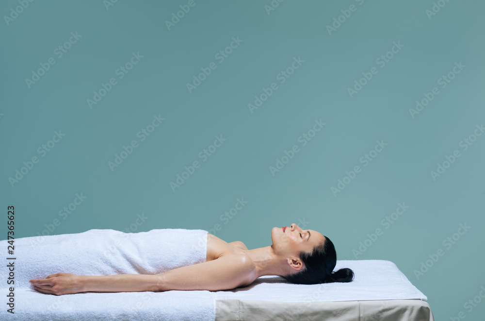 Beautiful Caucasian woman lying on massage table waiting for spa treatment.