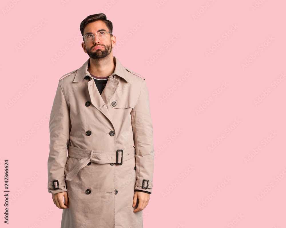 Young man wearing trench coat tired and bored Young man wearing trench coat tired and bored