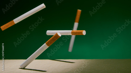 Cigarettes fall on a green background.