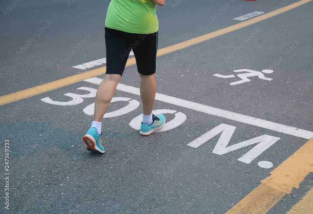 Closeup of woman's feet jogging in running track on the road in the evening. The good way of health promotion. 