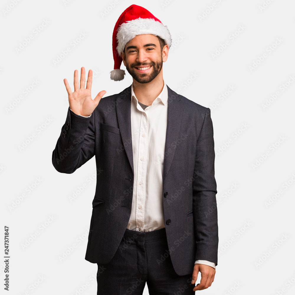 Young business man wearing santa hat showing number five Young business man wearing santa hat showing number five