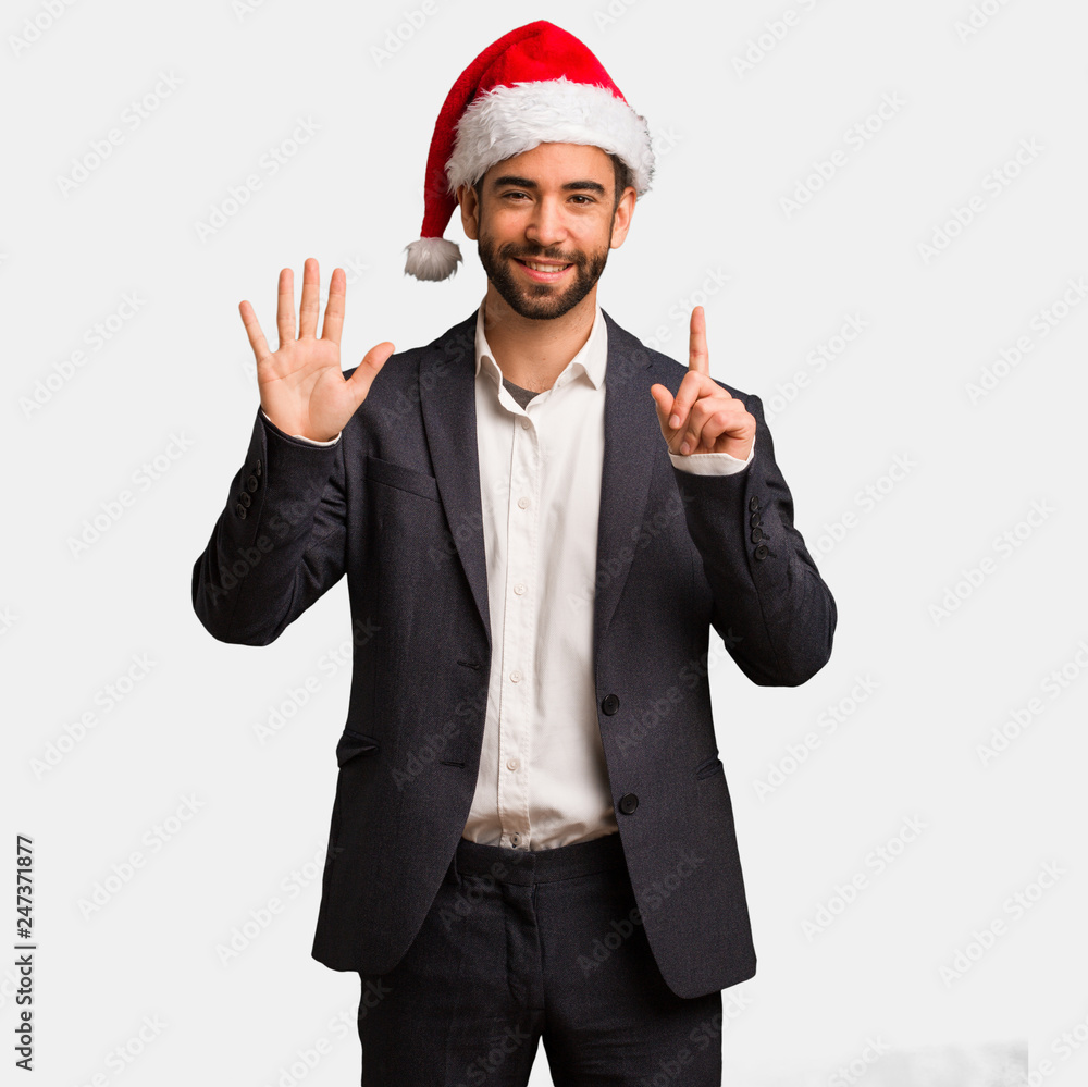 Young business man wearing santa hat showing number six