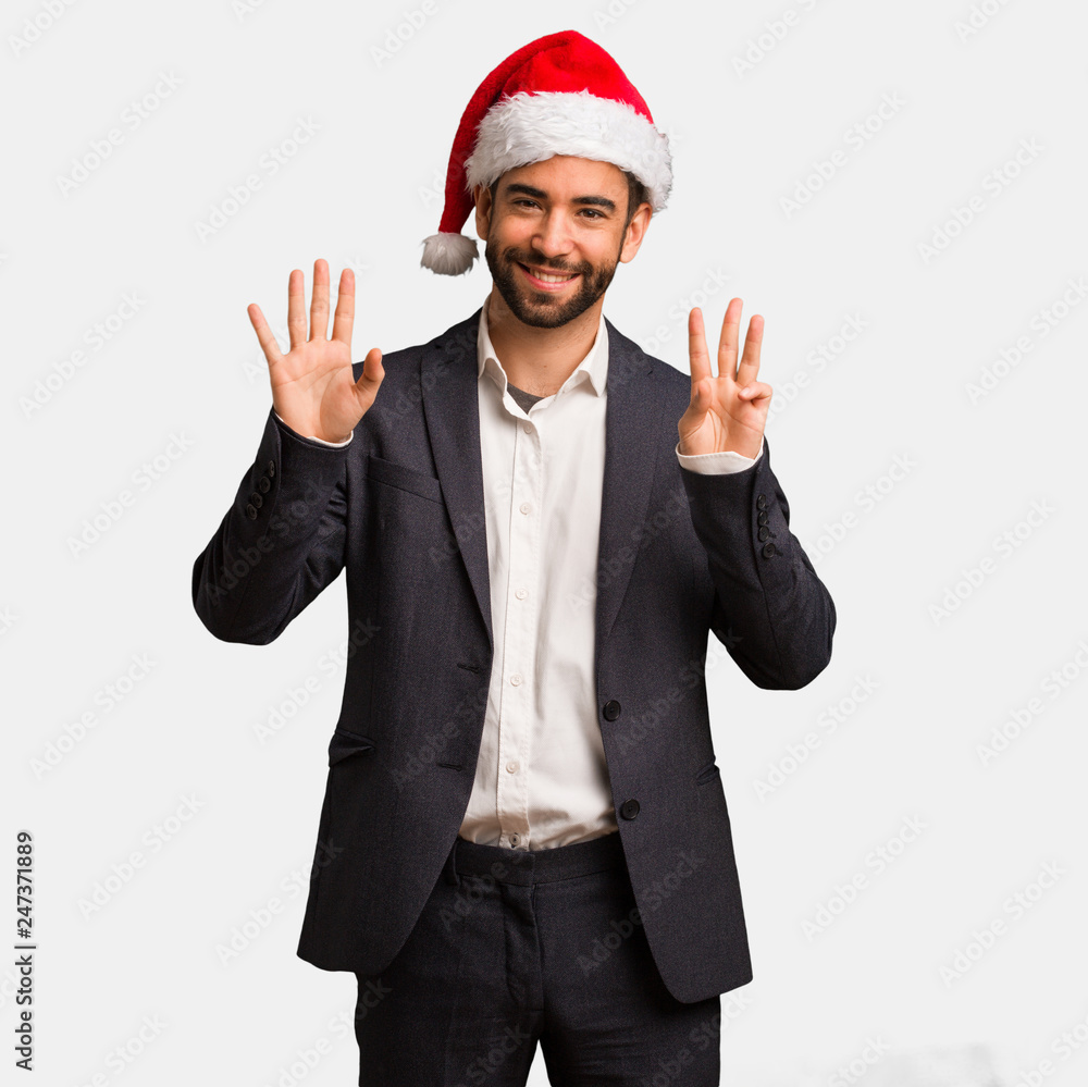 Young business man wearing santa hat showing number eight