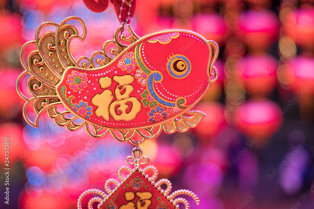 chinese symbol on fish decoration is hanging on with festival blur in background, the word mean luck