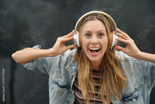 Dynamic young student listening to music with headphones on black background