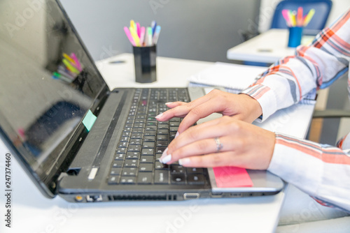 Office scene with young woman working on a laptop