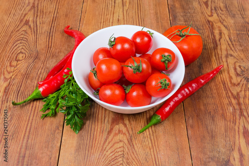 Red cherry tomatoes in white bowl and other vegetables