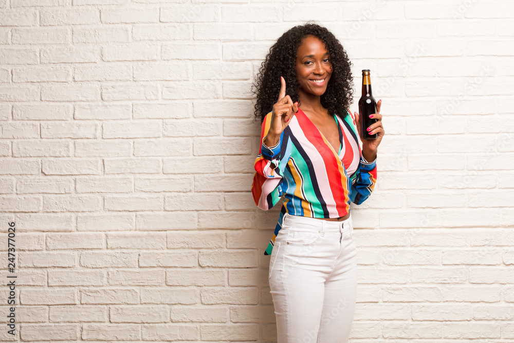 Young black woman showing number one, symbol of counting, concept of mathematics, confident and cheerful Young black woman showing number one, symbol of counting, concept of mathematics, confident and cheerful