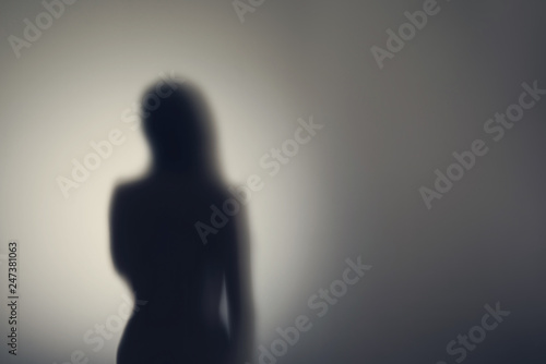 Silhouette of naked woman's body  behind glass door. Concept