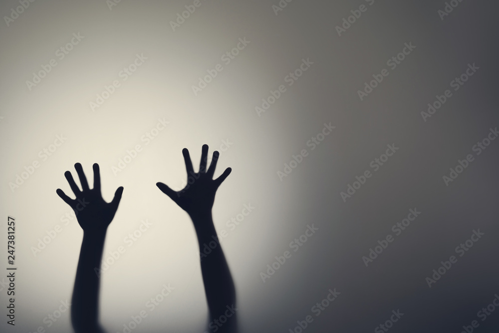 Dark silhouette of woman hands behind glass door. Concept of depression, fear, panic attacks