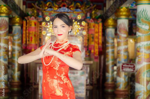 happy Chinese new year. Asian girl with gesture of congratulation on Chinese temple background.