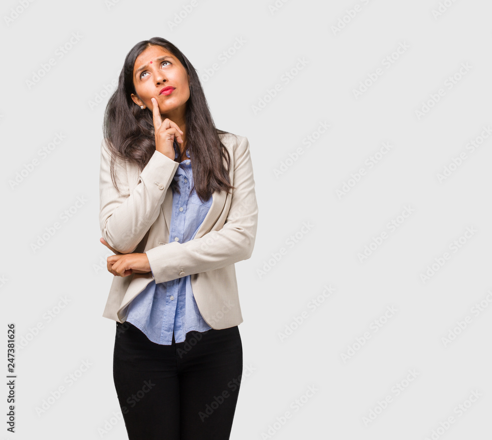 Young business indian woman doubting and confused, thinking of an idea or worried about something Young business indian woman doubting and confused, thinking of an idea or worried about something