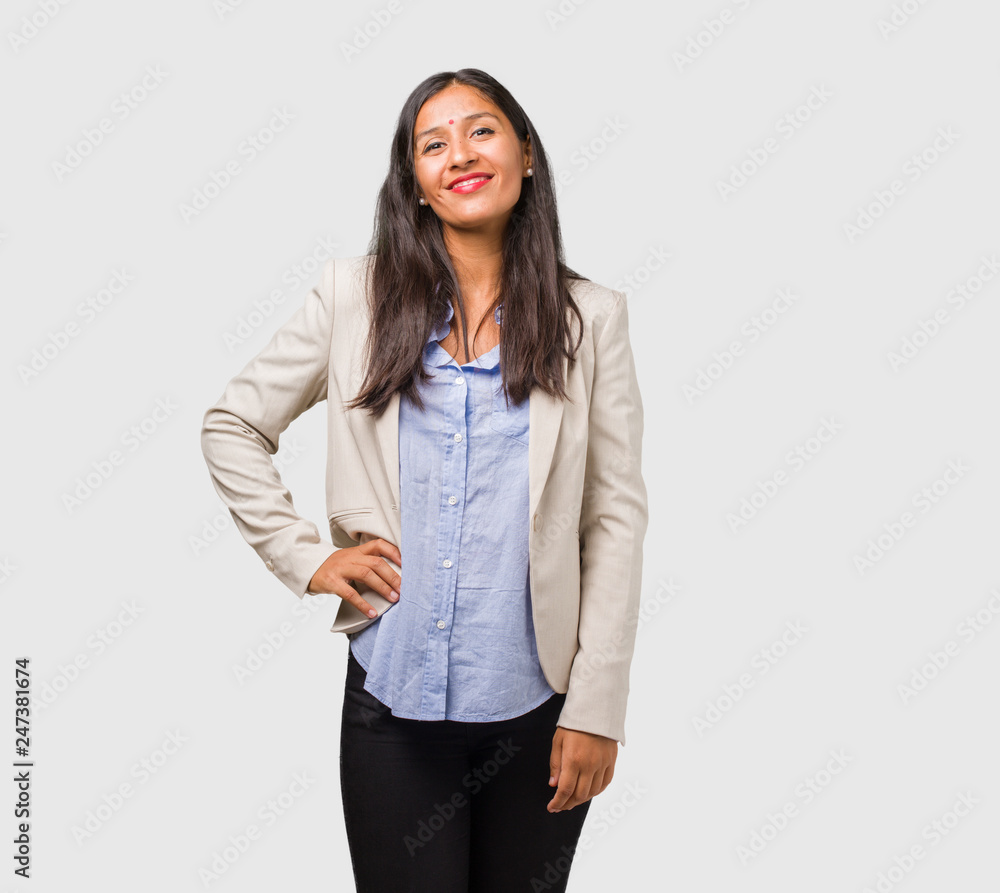 Young business indian woman with hands on hips, standing, relaxed and smiling, very positive and cheerful Young business indian woman with hands on hips, standing, relaxed and smiling, very positive and cheerful