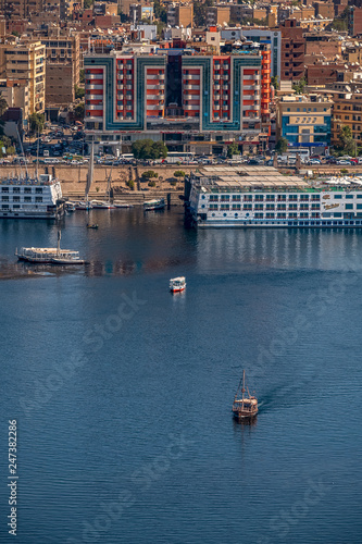 12.11.2018 Aswan, Egypt, A boat felucca sailing along a river of nilies on a sunny day against a city background photo