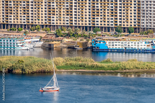 12.11.2018 Aswan, Egypt, A boat felucca sailing along a river of nilies on a sunny day against a city background photo