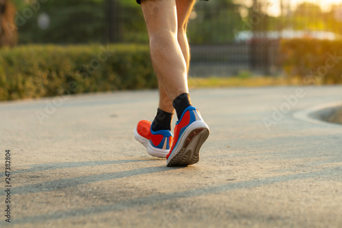 Sport background, close up of urban runner's legs run on the street of public park with copy space.