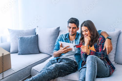 Online order. Couple making call to food delivery while sitting on sofa at new apartment