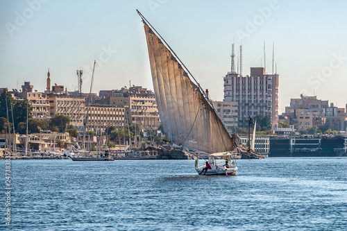 12.11.2018 Aswan, Egypt, A boat felucca sailing along a river of nilies on a sunny day against a city background photo