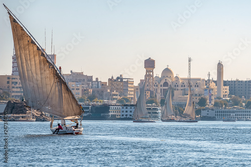 12.11.2018 Aswan, Egypt, A boat felucca sailing along a river of nilies on a sunny day against a city background