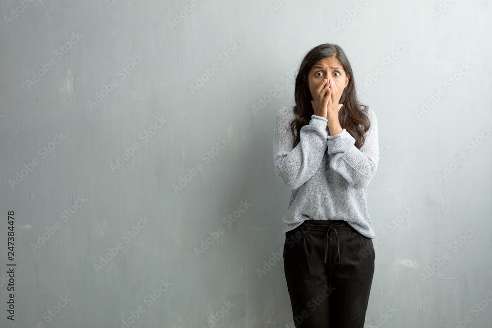 Young indian woman against a grunge wall very scared and afraid, desperate for something, cries of suffering and open eyes, concept of madness Young indian woman against a grunge wall very scared and afraid, desperate for something, cries of suffering and open eyes, concept of madness