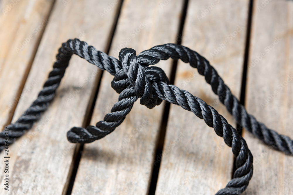A clove hitch tied on a length of rope on a wooden background.