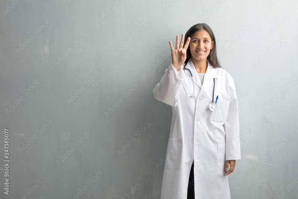 Young indian doctor woman against a wall showing the number four, symbol of counting, concept of mathematics, confident and cheerful Young indian doctor woman against a wall showing the number four, symbol of counting, concept of mathematics, confident and cheerful