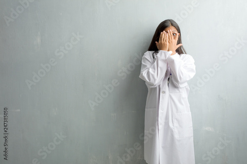 Принти на полотні Young indian doctor woman against a wall feels worried and scared, looking and c