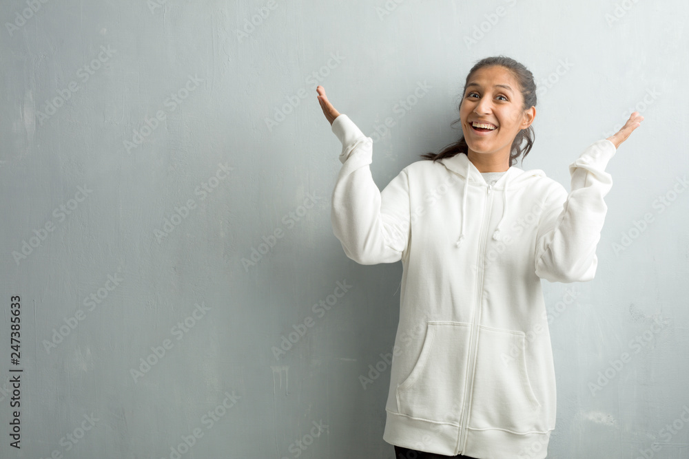 Young sporty indian woman against a gym wall laughing and having fun, being relaxed and cheerful, feels confident and successful Young sporty indian woman against a gym wall laughing and having fun, being relaxed and cheerful, feels confident and successful