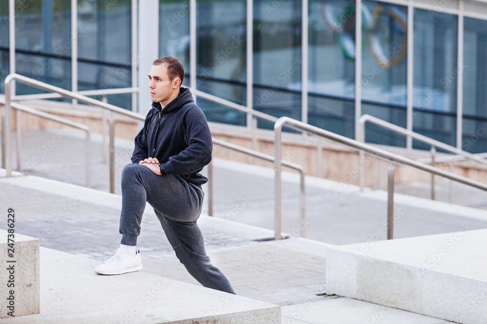 Portrait of a positive young man bodybuilding coach doing morning workout outside in scenic spots. Concept of preparation for competitions and a healthy lifestyle Portrait of a positive young man bodybuilding coach doing morning workout outside in scenic spots. Concept of preparation for competitions and a healthy lifestyle