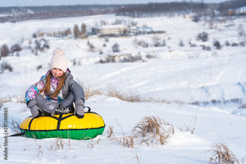 Young little girl laughing and enjoying snow tubing on the snowy hill at winter © Ievgen Skrypko