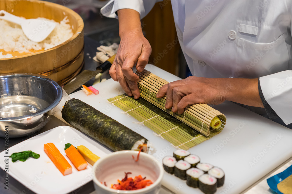 Sushi chef prepares maki rolls