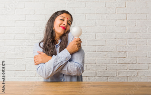 Young indian woman proud and confident, pointing fingers, example to follow, concept of satisfaction, arrogance and health. Holding a light bulb.