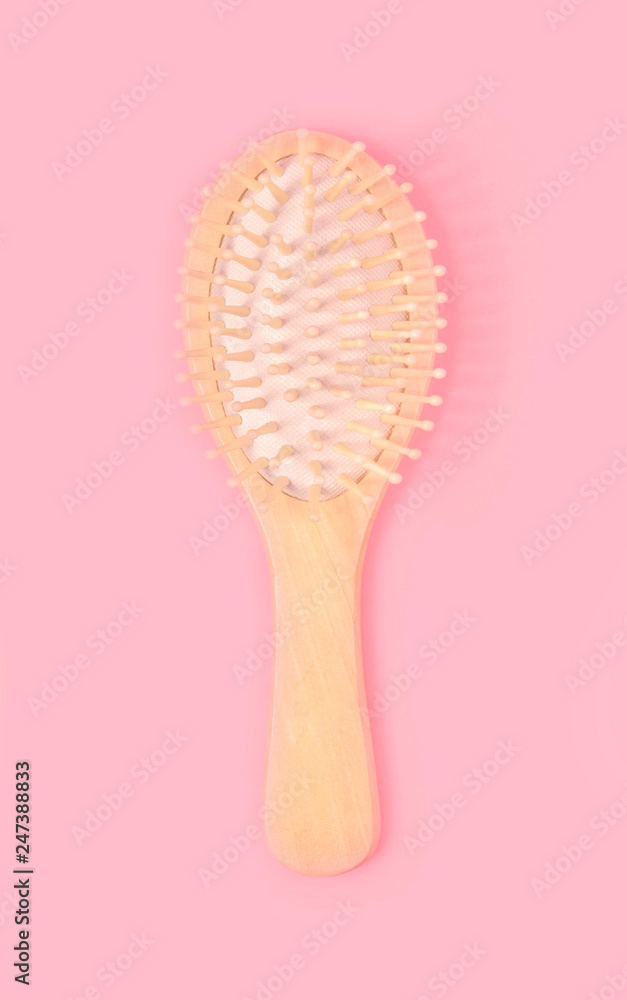 Wooden hairbrush made of natural oak on pastel pink background. Wooden hairbrush made of natural oak on pastel pink background.