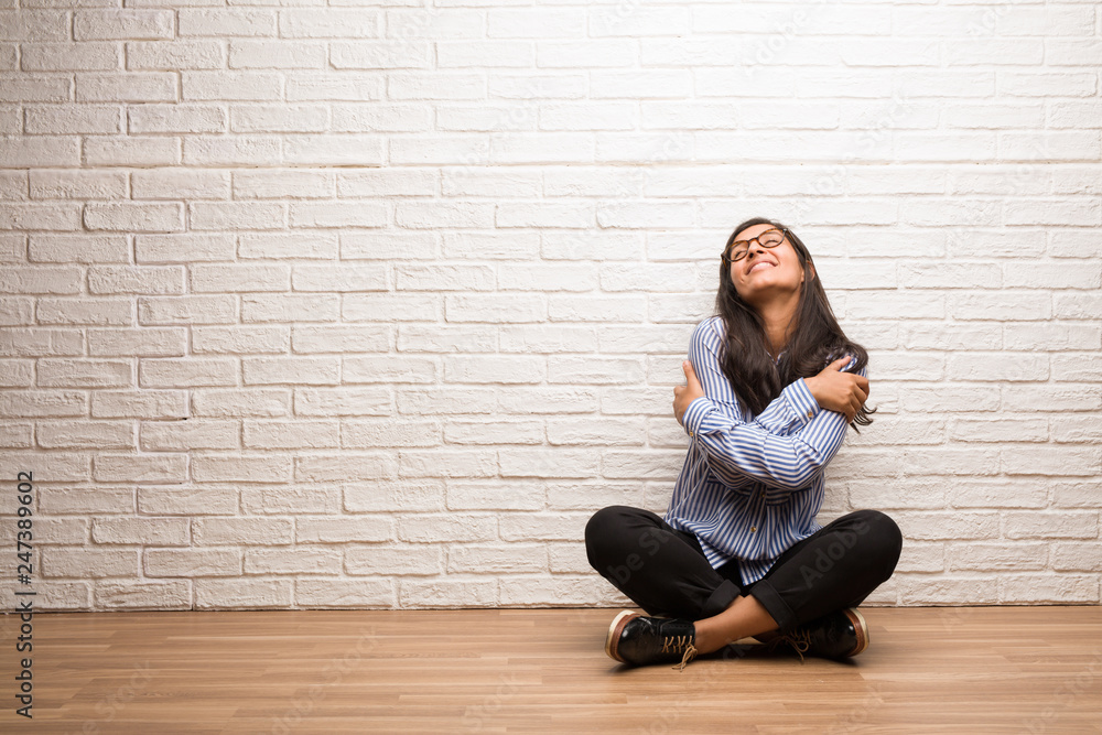 Young indian woman sit against a brick wall proud and confident, pointing fingers, example to follow, concept of satisfaction, arrogance and health Young indian woman sit against a brick wall proud and confident, pointing fingers, example to follow, concept of satisfaction, arrogance and health