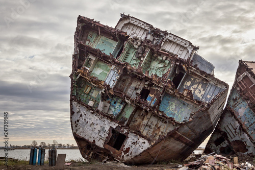 Huge rusty pieces of decommissioned marine ship that was cut and left on the shore. photo