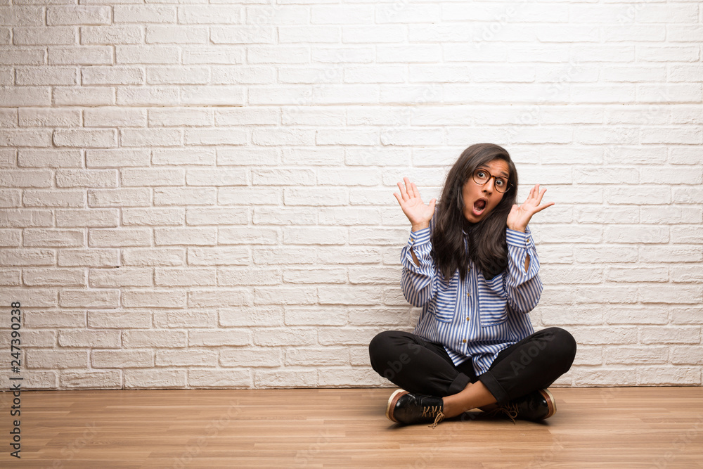 Young indian woman sit against a brick wall crazy and desperate, screaming out of control, funny lunatic expressing freedom and wild Young indian woman sit against a brick wall crazy and desperate, screaming out of control, funny lunatic expressing freedom and wild