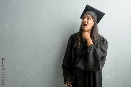 Young graduated indian woman against a wall worried and overwhelmed, anxious feeling pressure, concept of anguish