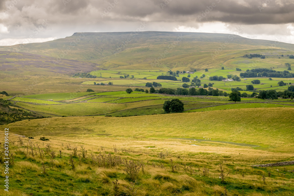 a valley of farm land and hills in England. Handmade stone walls and fields. 