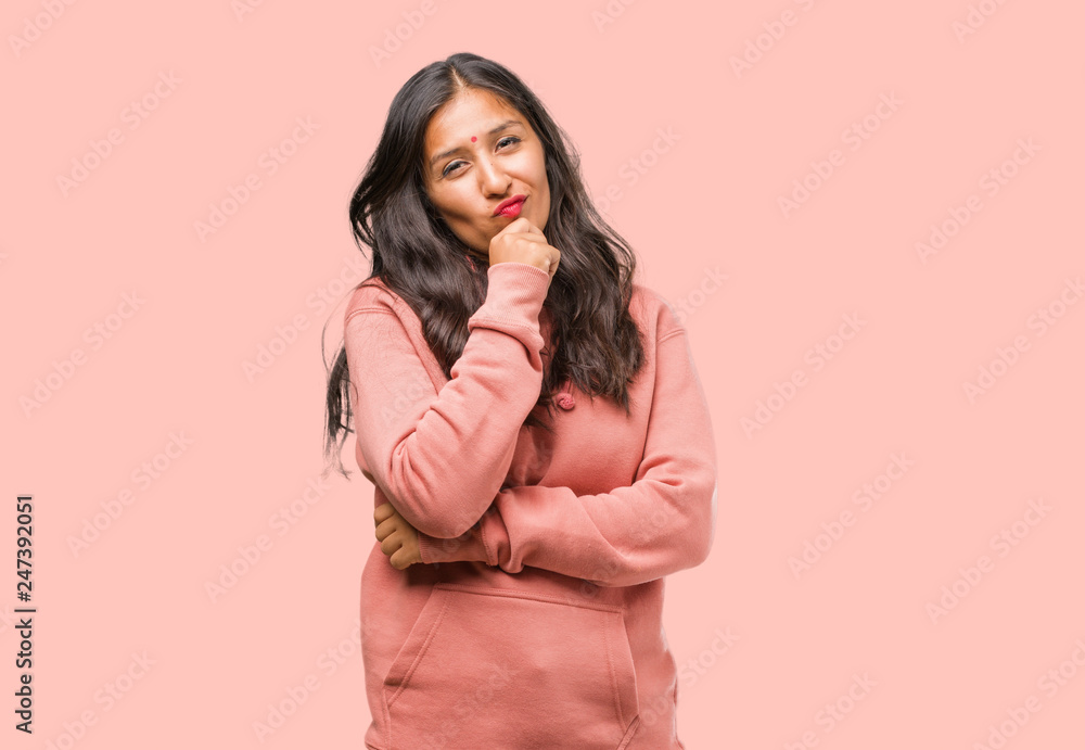 Portrait of fitness young indian woman thinking and looking up, confused about an idea, would be trying to find a solution Portrait of fitness young indian woman thinking and looking up, confused about an idea, would be trying to find a solution