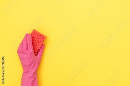 Woman holding pink sponge for washing in her hands against yellow background