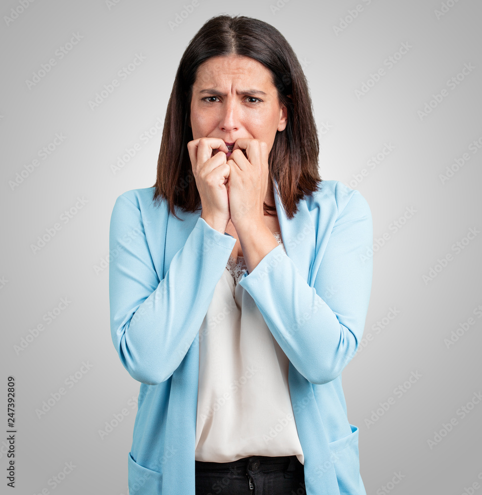 Middle aged woman biting nails, nervous and very anxious and scared for the future, feels panic and stress