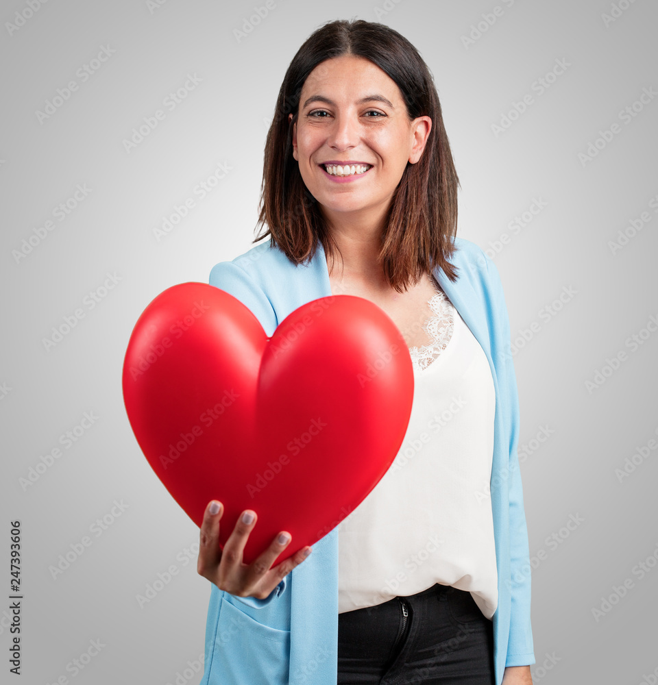 Middle aged woman cheerful and confident, offering a heart shape towards the front, concept of love, companionship and friendship Middle aged woman cheerful and confident, offering a heart shape towards the front, concept of love, companionship and friendship
