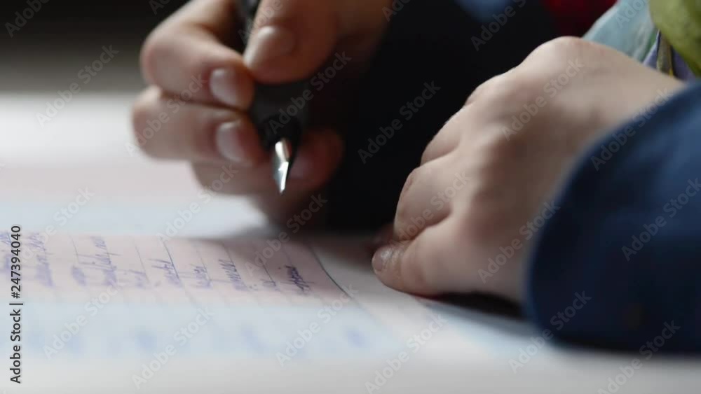 A pair of kids hands writing on paper very close up shot A pair of kids hands writing on paper very close up shot