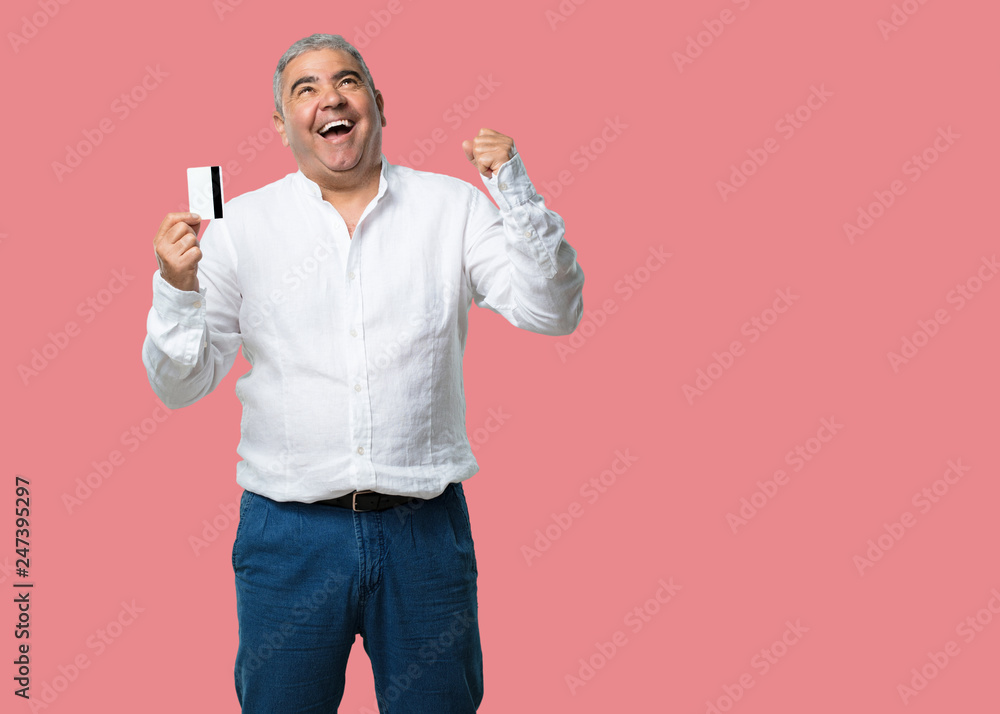 Middle aged man cheerful and smiling, very excited holding the new bank card, ready to go shopping Middle aged man cheerful and smiling, very excited holding the new bank card, ready to go shopping