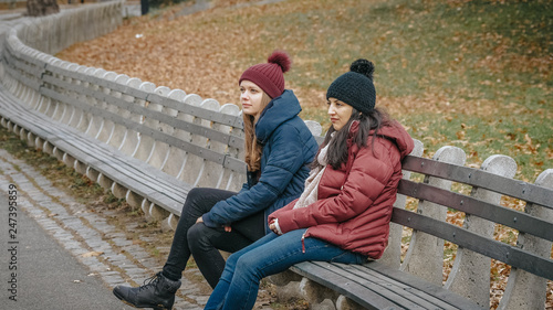 Two girls in Central Park New York sit on a bench to relax